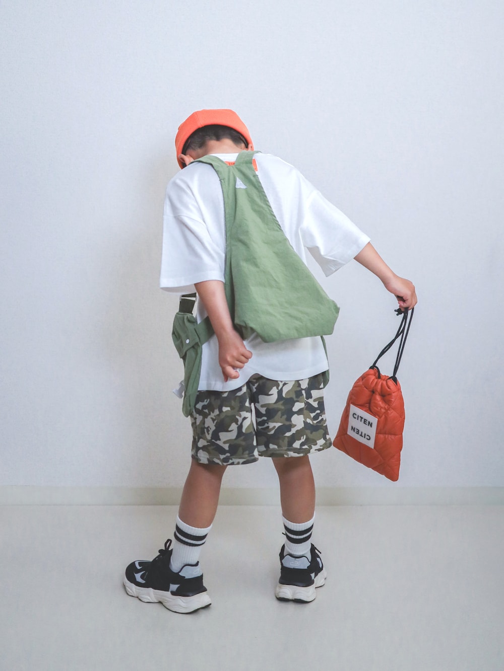 グリーン系のスウェットパンツ、ホワイト系のTシャツ/カットソー、オレンジ系のショルダーバッグを着用したキッズの春コーディネートの2枚目の写真