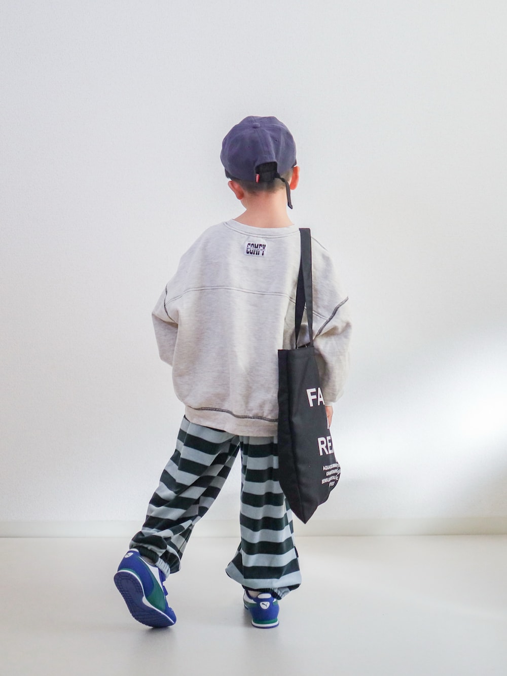 ブルー系のスウェットパンツ、ベージュ系のスウェット、ホワイト系のスニーカーを着用したキッズの冬コーディネートの3枚目の写真