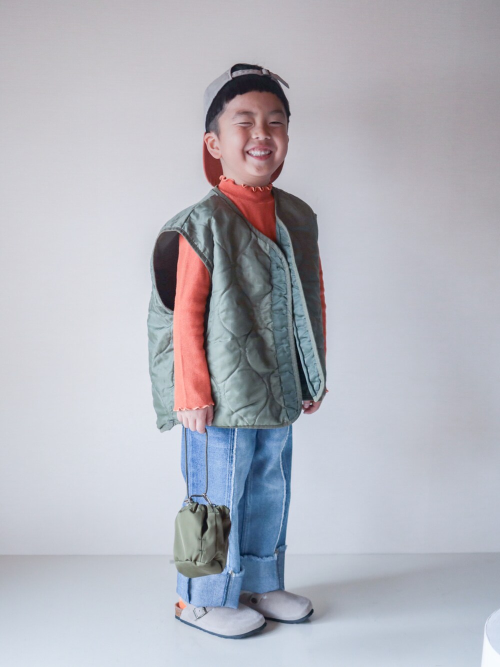ブルー系のデニムパンツ、オレンジ系のTシャツ/カットソー、ベージュ系のサンダルを着用したキッズの春コーディネートの5枚目の写真