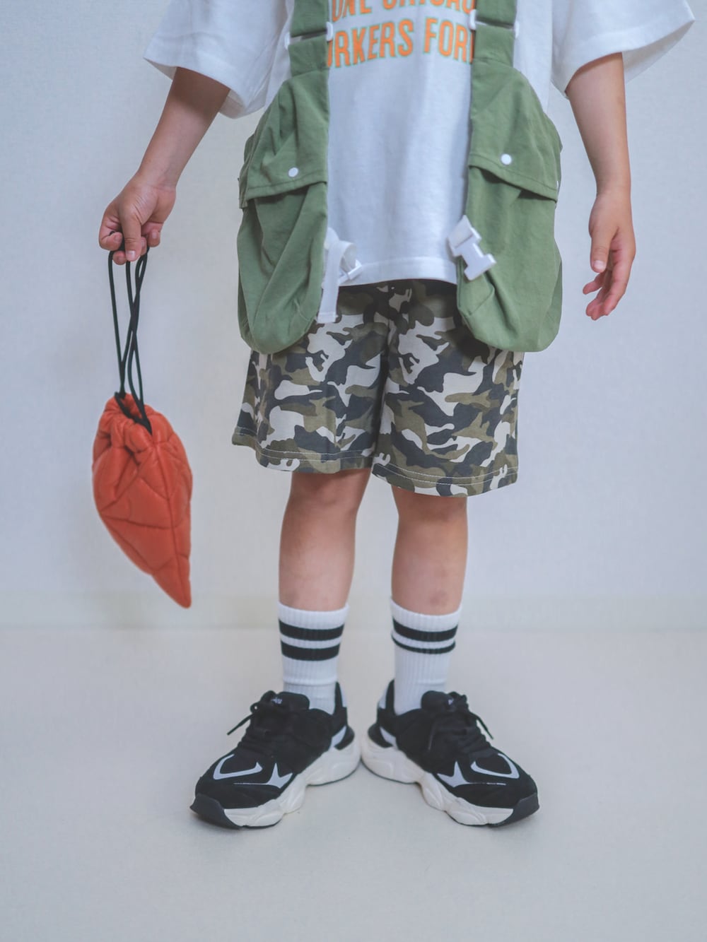 グリーン系のスウェットパンツ、ホワイト系のTシャツ/カットソー、オレンジ系のショルダーバッグを着用したキッズの春コーディネートの3枚目の写真