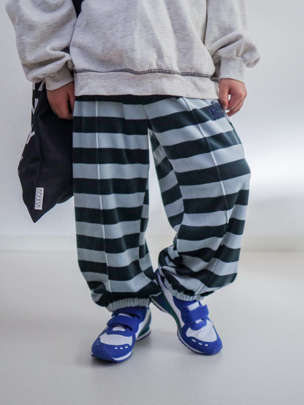 ブルー系のスウェットパンツ、ベージュ系のスウェット、ホワイト系のスニーカーを着用したキッズの冬コーディネートの4枚目の写真