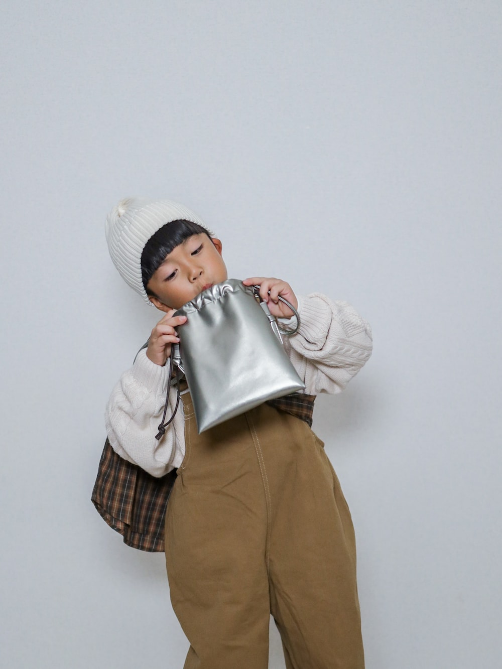 ホワイト系のニット/セーター、ブラウン系のシャツ/ブラウス、ブラウン系のサロペット/オーバーオールを着用したキッズの秋コーディネートの4枚目の写真