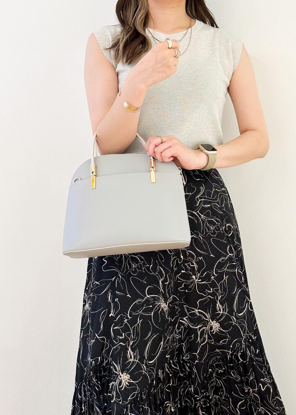 グレー系のニット/セーター、グレー系のショルダーバッグ、ブラック系のスカートを着用したレディースの夏コーディネートの6枚目の写真