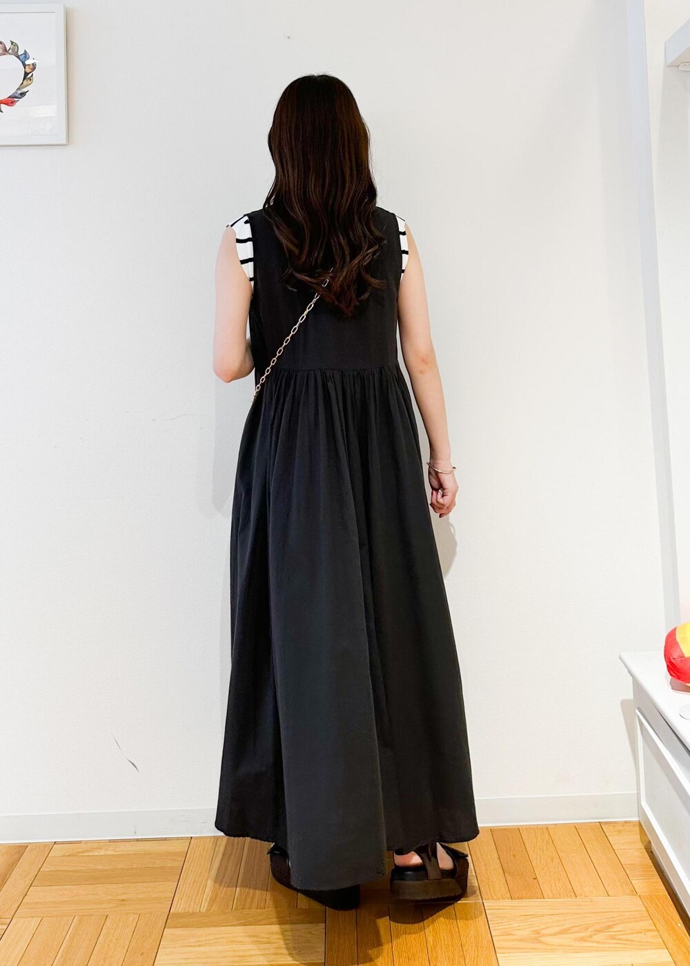 シルバー系のショルダーバッグ、ホワイト系のニット/セーター、ブラック系のワンピースを着用したレディースの夏コーディネートの2枚目の写真