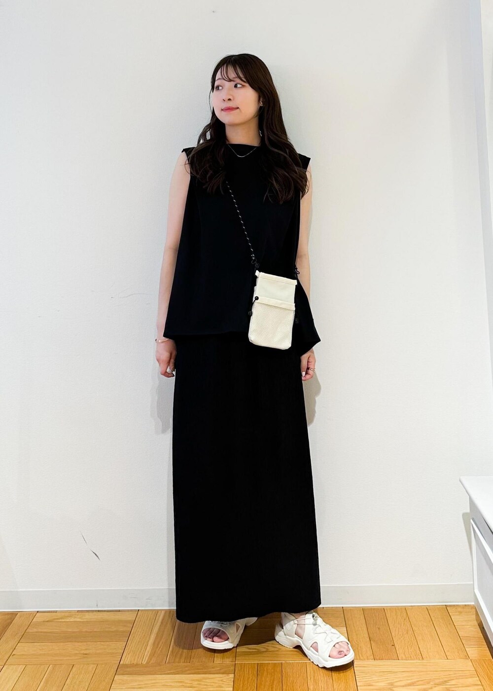 ホワイト系のショルダーバッグ、ブラック系のスカート、ホワイト系のサンダルを着用したレディースの春コーディネートの2枚目の写真