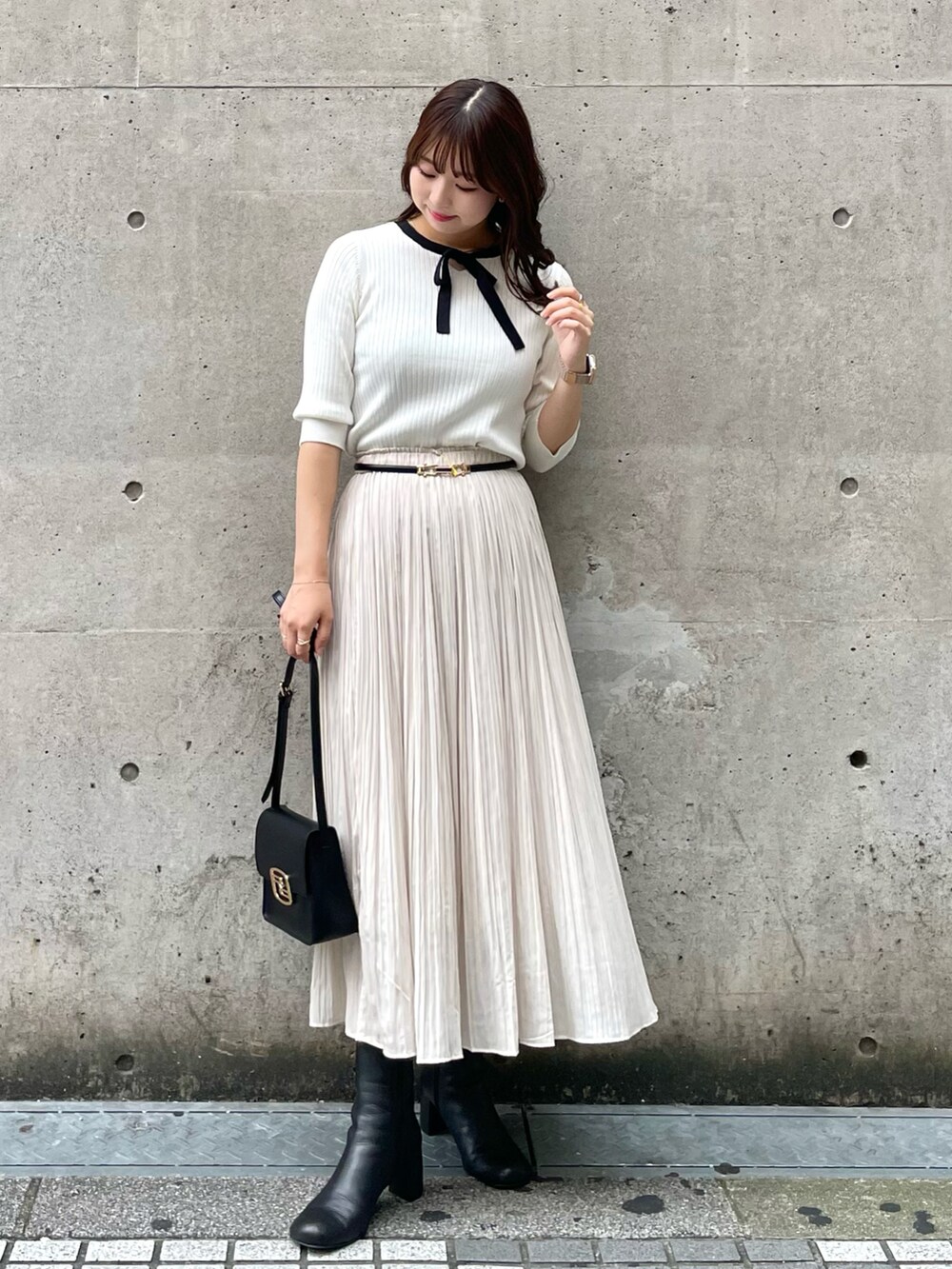 ブラック系のショルダーバッグ、ブラック系のベスト、ホワイト系のニット/セーターを着用したレディースの秋コーディネートの3枚目の写真