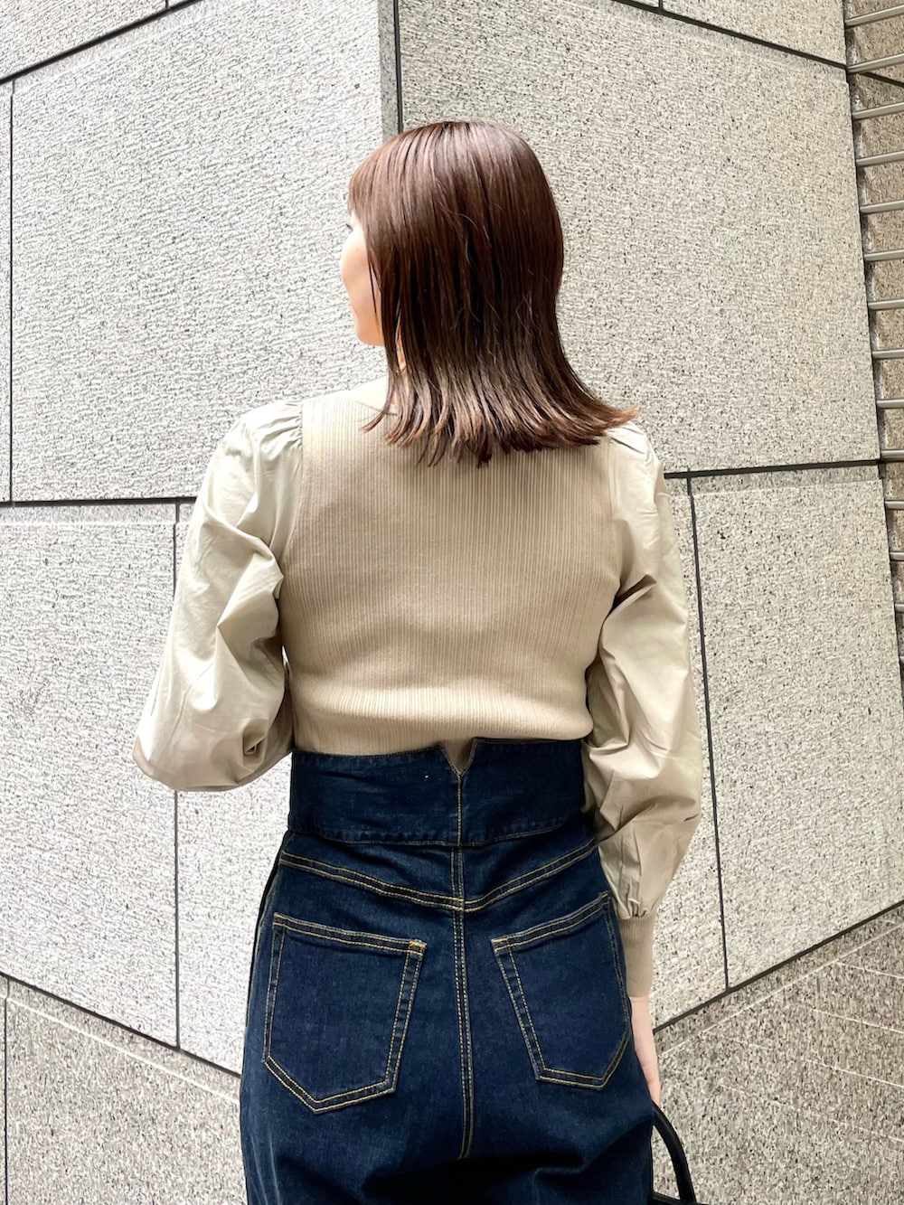 ベージュ系のニット/セーター、ブルー系のデニムパンツ、ブラック系のトートバッグを着用したレディースの春コーディネートの4枚目の写真