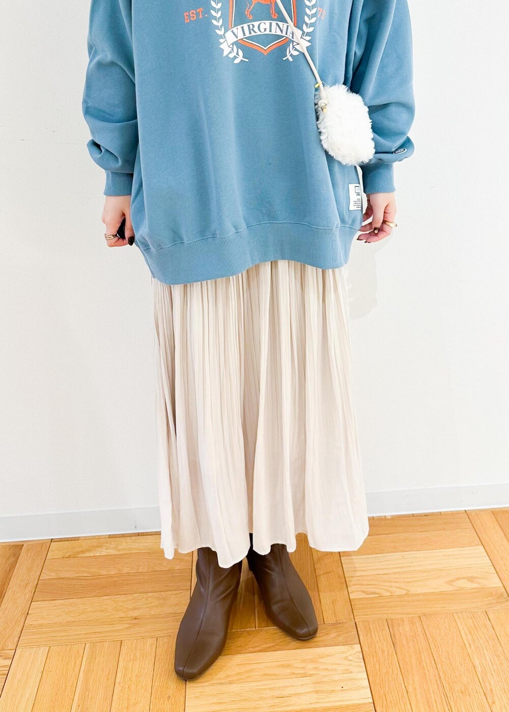 ベージュ系のスカート、ホワイト系のショルダーバッグ、グリーン系のスウェットを着用したレディースの秋コーディネートの7枚目の写真