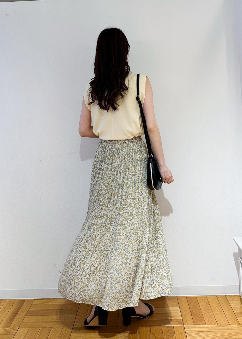 ベージュ系のニット/セーター、イエロー系のスカート、ブラック系のショルダーバッグを着用したレディースの春コーディネートの3枚目の写真