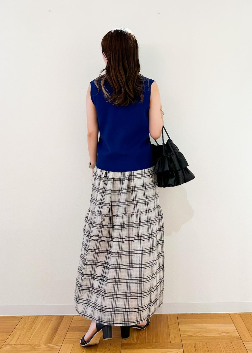 ブラック系のトートバッグ、ブルー系のベスト、ブラック系のスカートを着用したレディースの夏コーディネートの3枚目の写真