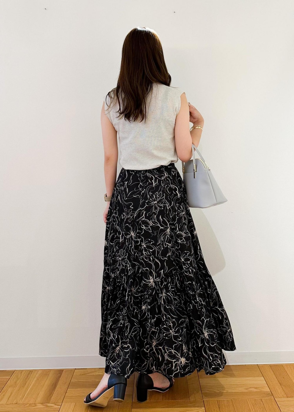 グレー系のニット/セーター、グレー系のショルダーバッグ、ブラック系のスカートを着用したレディースの夏コーディネートの3枚目の写真