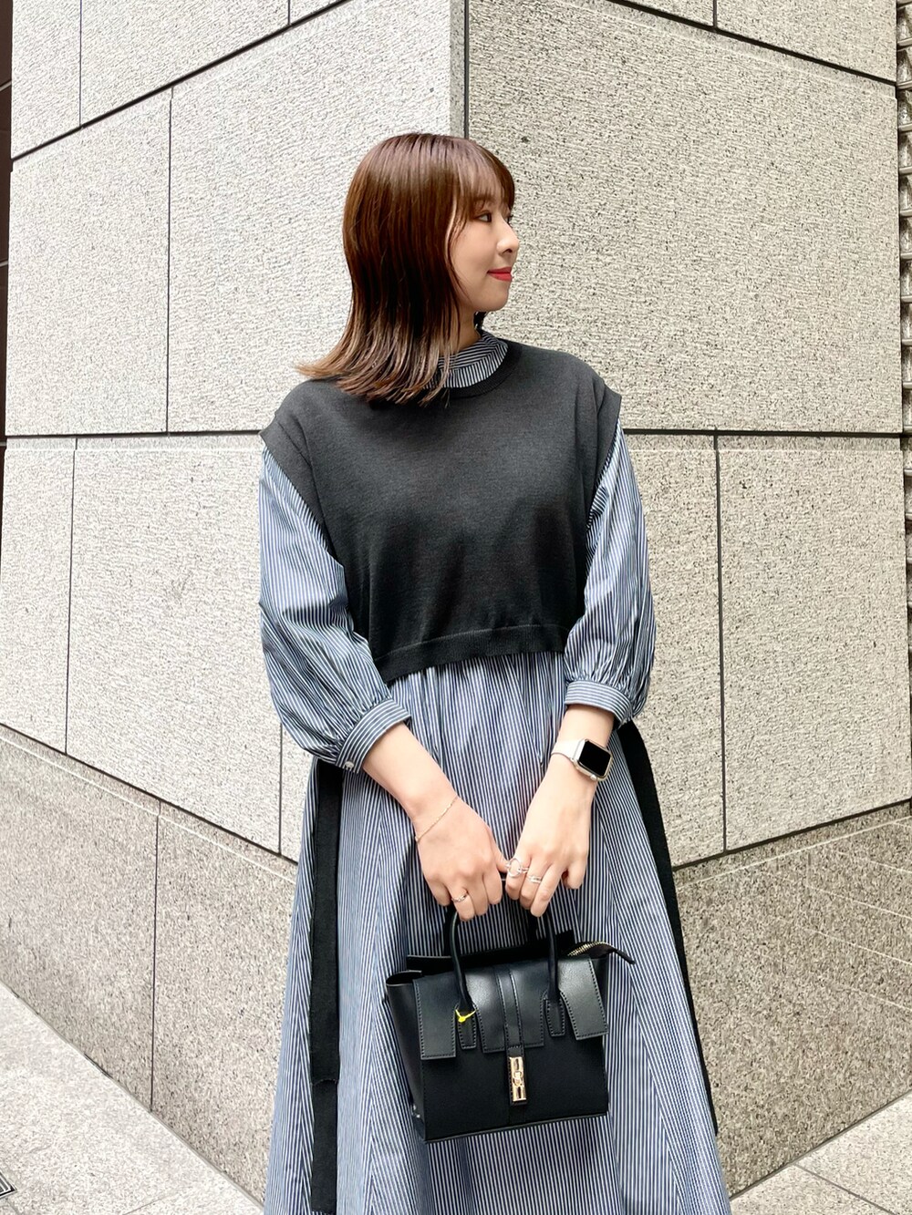 ブラック系のベスト、ブルー系のワンピース、ブラック系のショルダーバッグを着用したレディースの春コーディネートの3枚目の写真