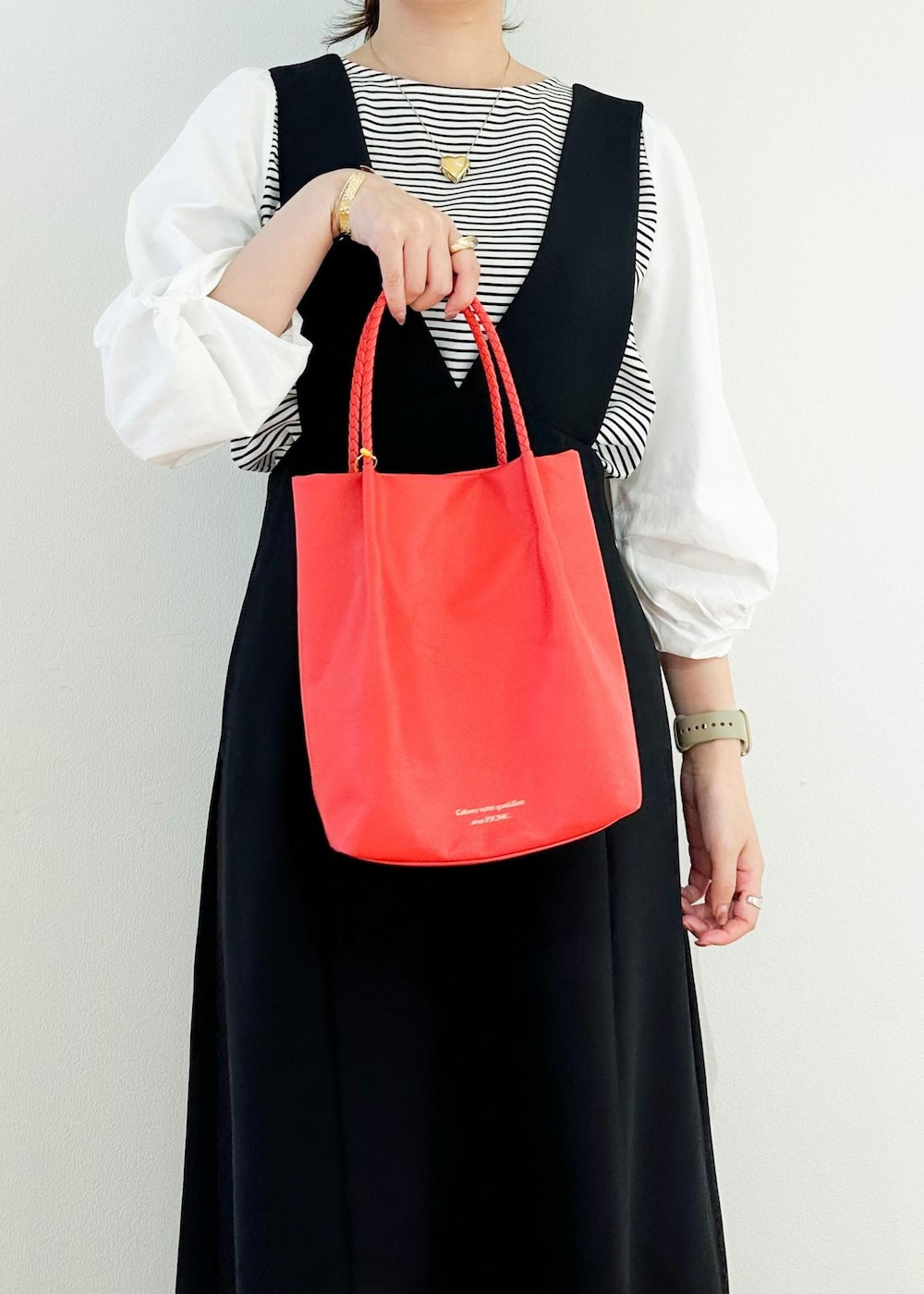 ブラック系のジャンパースカート、レッド系のトートバッグ、ブラック系のTシャツ/カットソーを着用したレディースの秋コーディネートの6枚目の写真