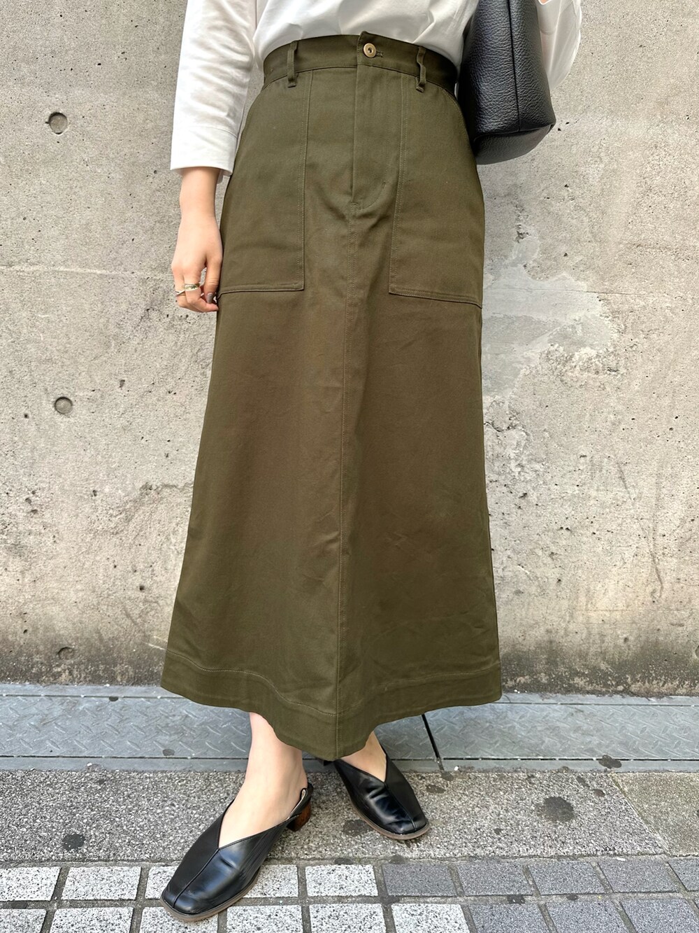 ホワイト系のTシャツ/カットソー、グリーン系のスカート、ブラック系のショルダーバッグを着用したレディースの春コーディネートの5枚目の写真