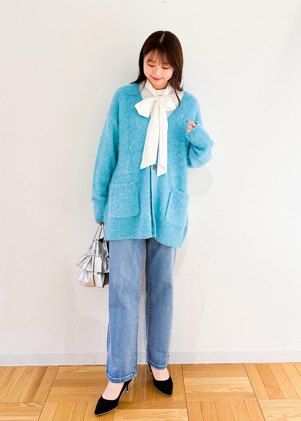 シルバー系のトートバッグ、ホワイト系のシャツ/ブラウス、グリーン系のカーディガン/ボレロを着用したレディースの秋コーディネートの2枚目の写真