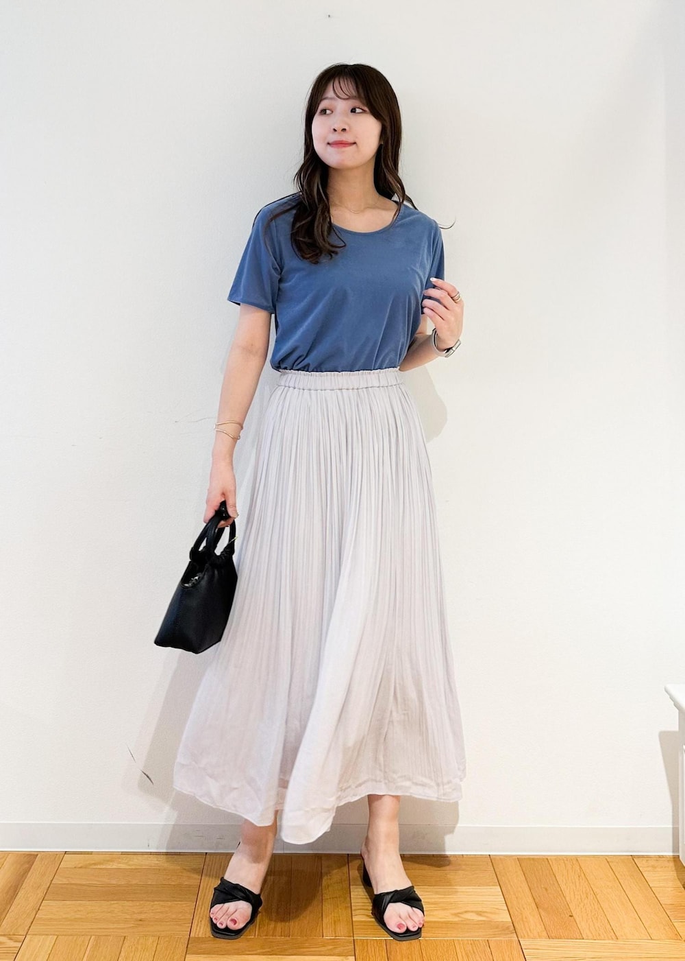 グレー系のスカート、ブラック系のショルダーバッグ、ブルー系のTシャツ/カットソーを着用したレディースの夏コーディネートの2枚目の写真