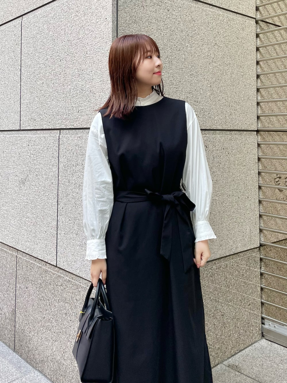 ホワイト系のシャツ/ブラウス、ブラック系のジャンパースカート、ブラック系のパンプスを着用したレディースの冬コーディネートの3枚目の写真
