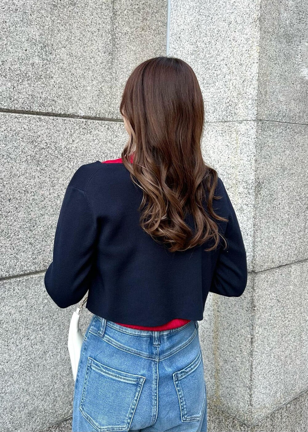 レッド系のニット/セーター、ブルー系のデニムパンツ、ブルー系のカーディガン/ボレロを着用したレディースの冬コーディネートの5枚目の写真