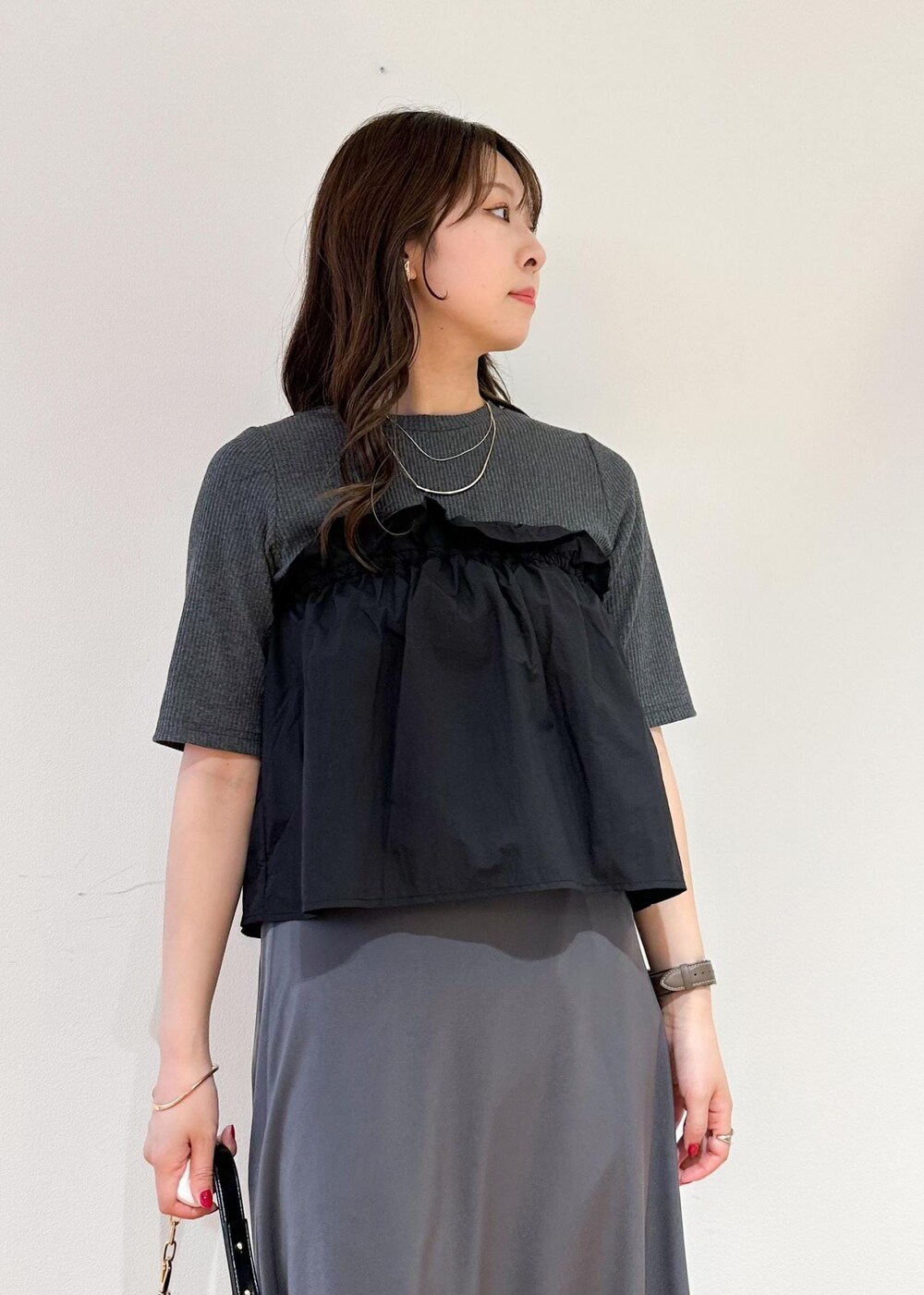 ブラック系のショルダーバッグ、グレー系のスカート、グレー系のニット/セーターを着用したレディースの夏コーディネートの4枚目の写真