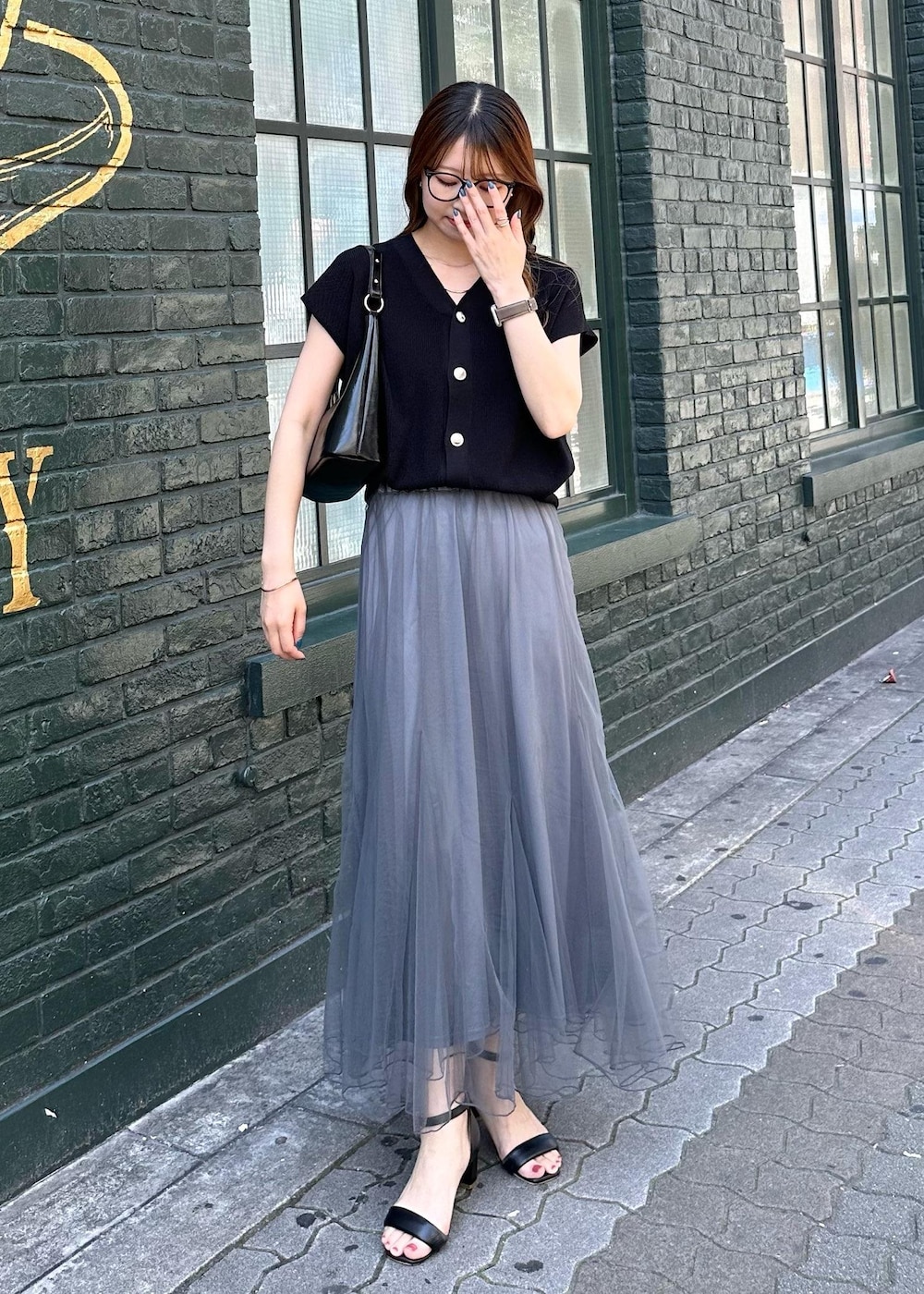 グレー系のスカート、ブラック系のニット/セーター、ブラック系のショルダーバッグを着用したレディースの春コーディネートの2枚目の写真