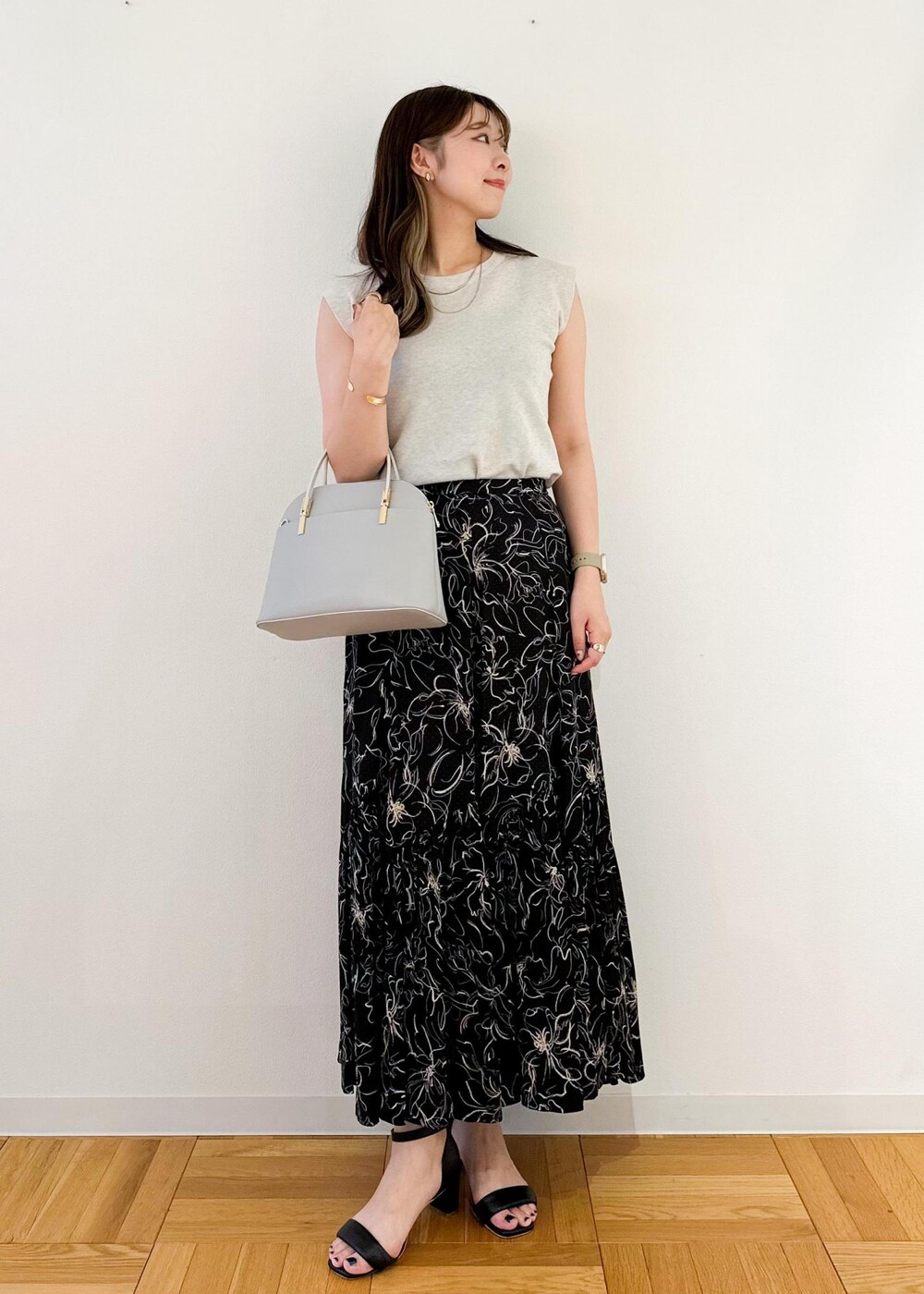 グレー系のニット/セーター、グレー系のショルダーバッグ、ブラック系のスカートを着用したレディースの夏コーディネートの2枚目の写真