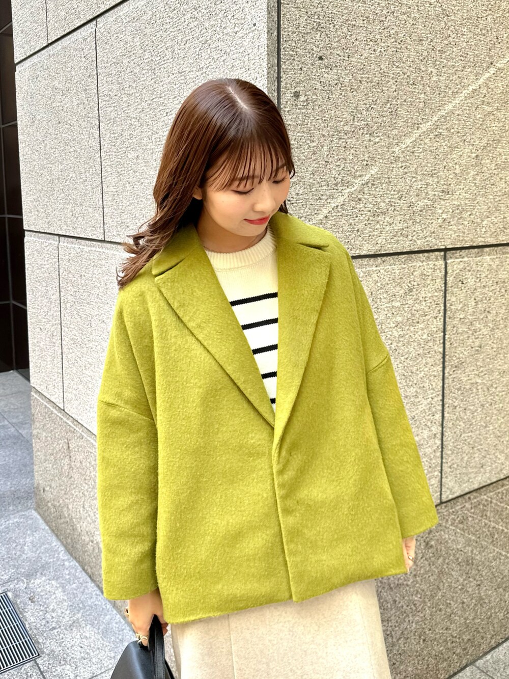 イエロー系のその他アウター、ベージュ系のスカート、ホワイト系のニット/セーターを着用したレディースの冬コーディネートの3枚目の写真