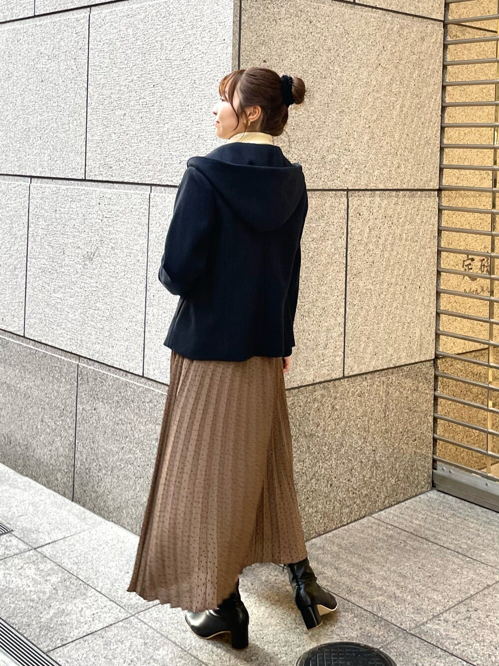 ブラウン系のスカート、ブラック系のショルダーバッグ、ブラック系のブーツを着用したレディースの秋コーディネートの2枚目の写真