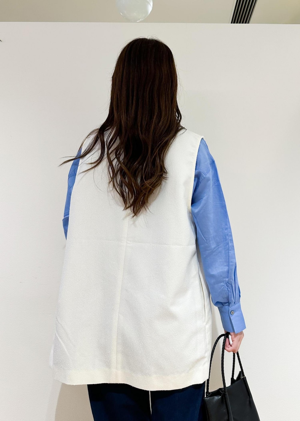 ブラック系のトートバッグ、ホワイト系のベスト、ブルー系のシャツ/ブラウスを着用したレディースの夏コーディネートの6枚目の写真