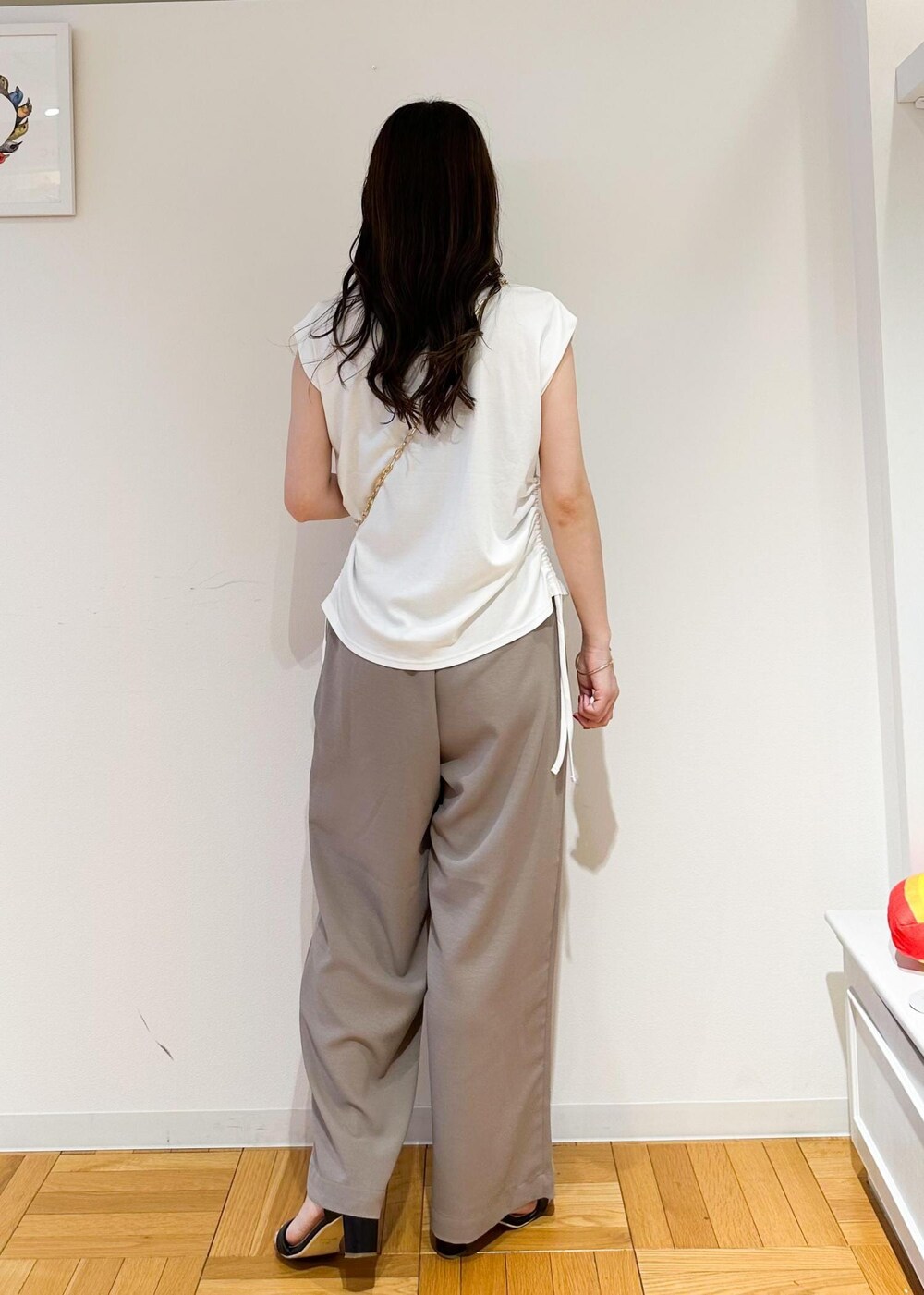 ブラック系のショルダーバッグ、ベージュ系のその他パンツ、ホワイト系のTシャツ/カットソーを着用したレディースの夏コーディネートの3枚目の写真