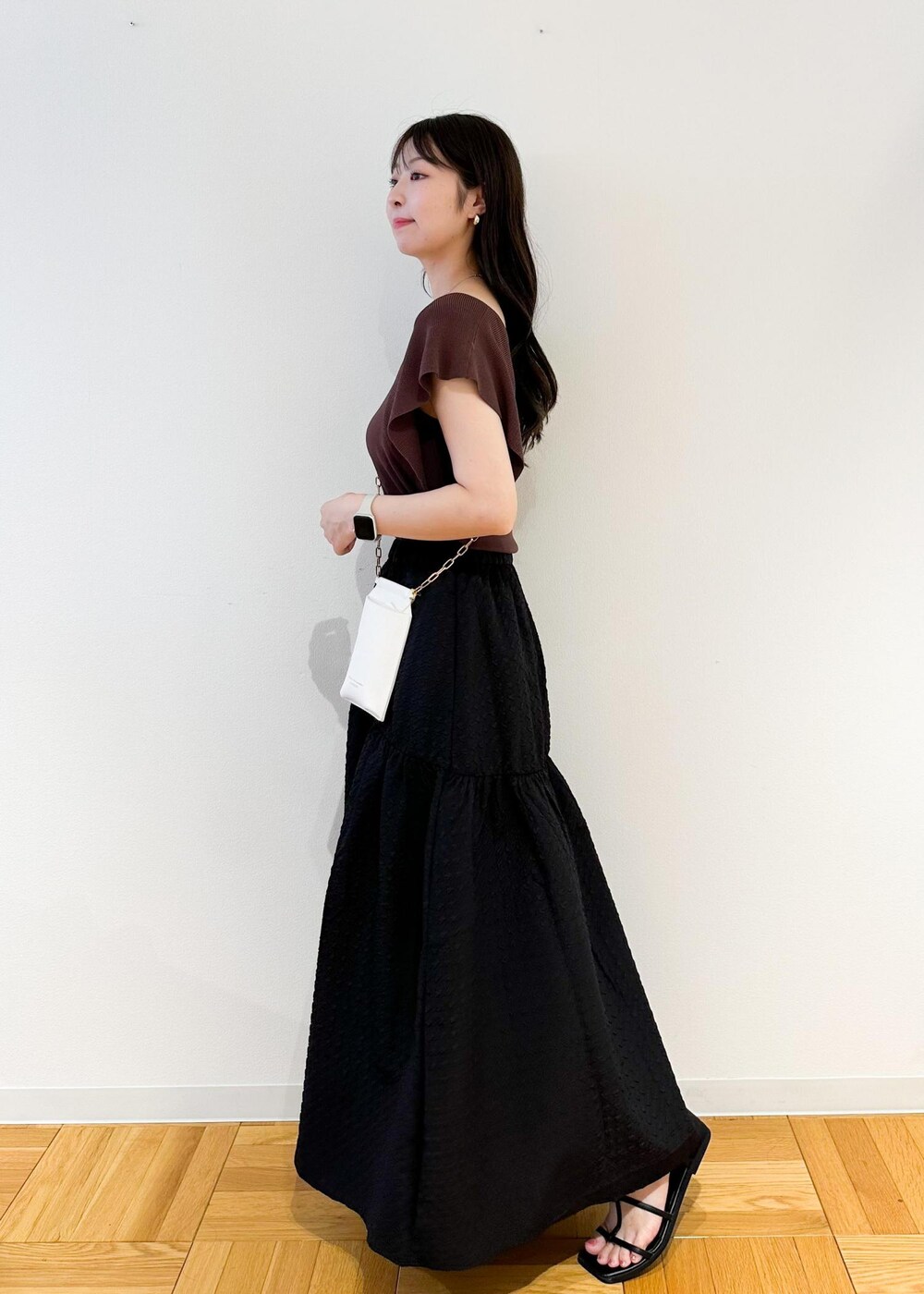 ホワイト系のショルダーバッグ、ブラウン系のニット/セーター、ブラック系のスカートを着用したレディースの夏コーディネートの3枚目の写真