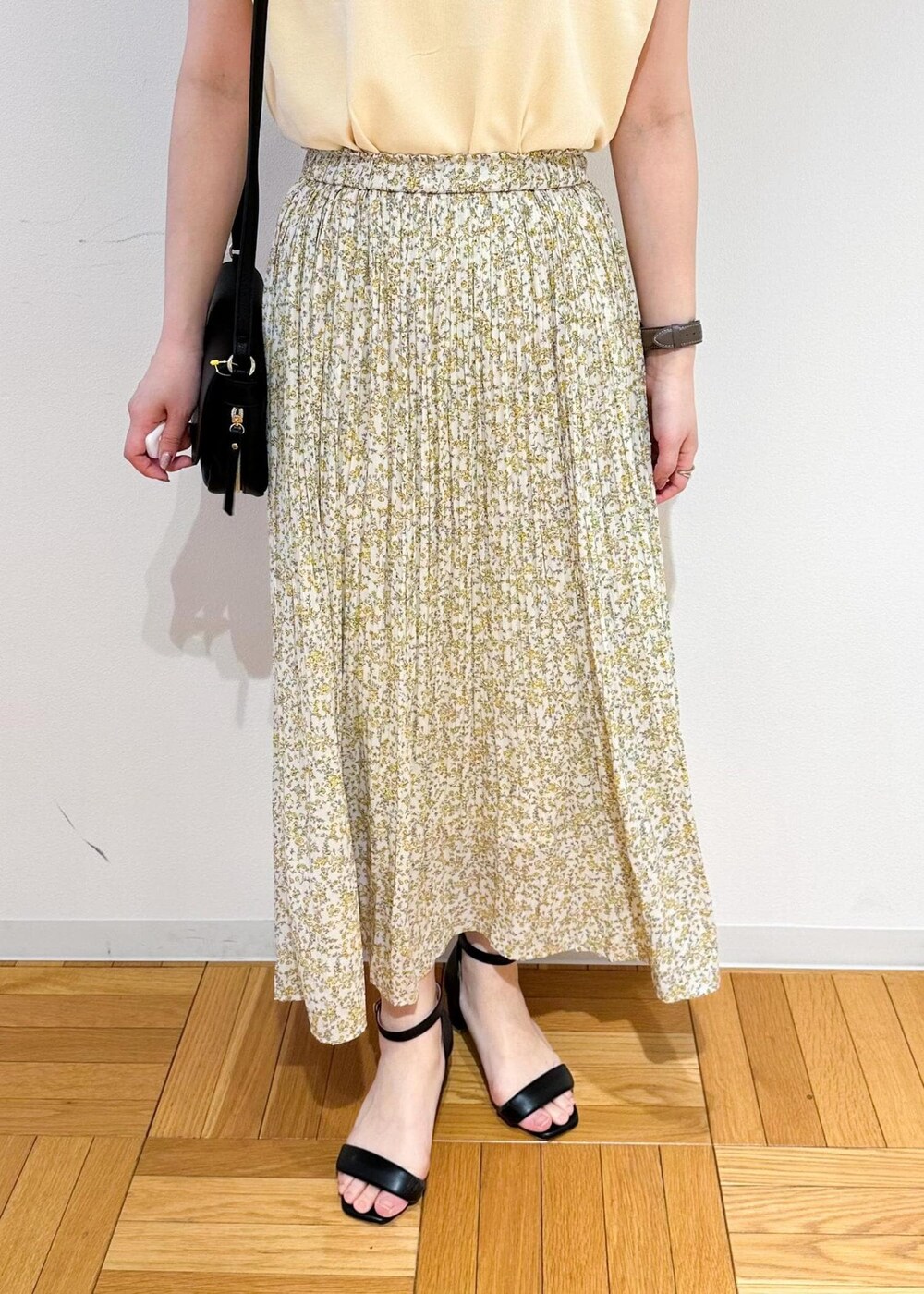 ベージュ系のニット/セーター、イエロー系のスカート、ブラック系のショルダーバッグを着用したレディースの春コーディネートの6枚目の写真