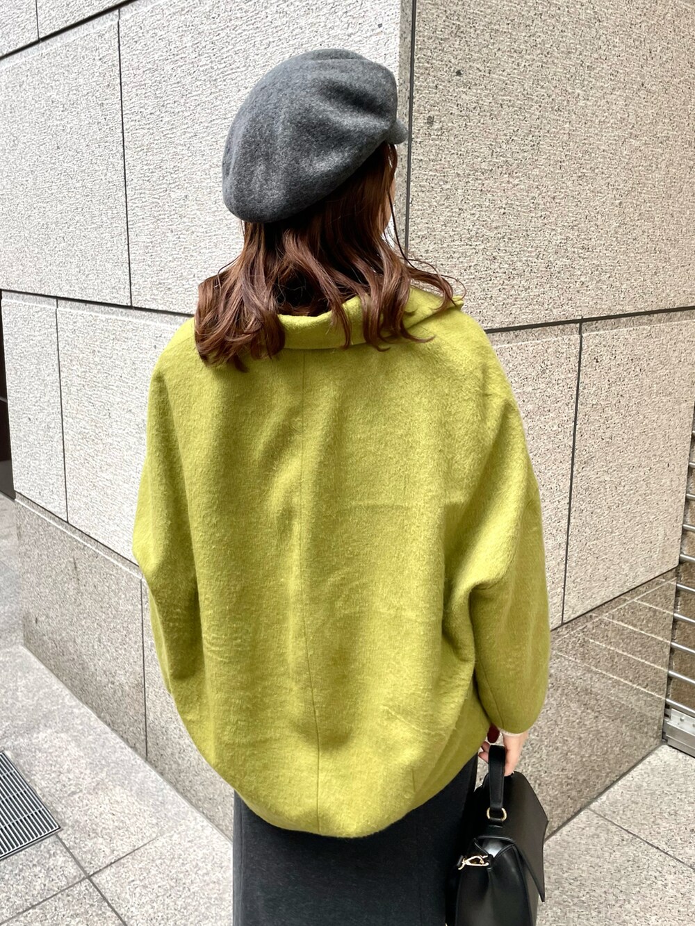 イエロー系のその他アウター、ブラック系のニット/セーター、ブラック系のショルダーバッグを着用したレディースの冬コーディネートの4枚目の写真