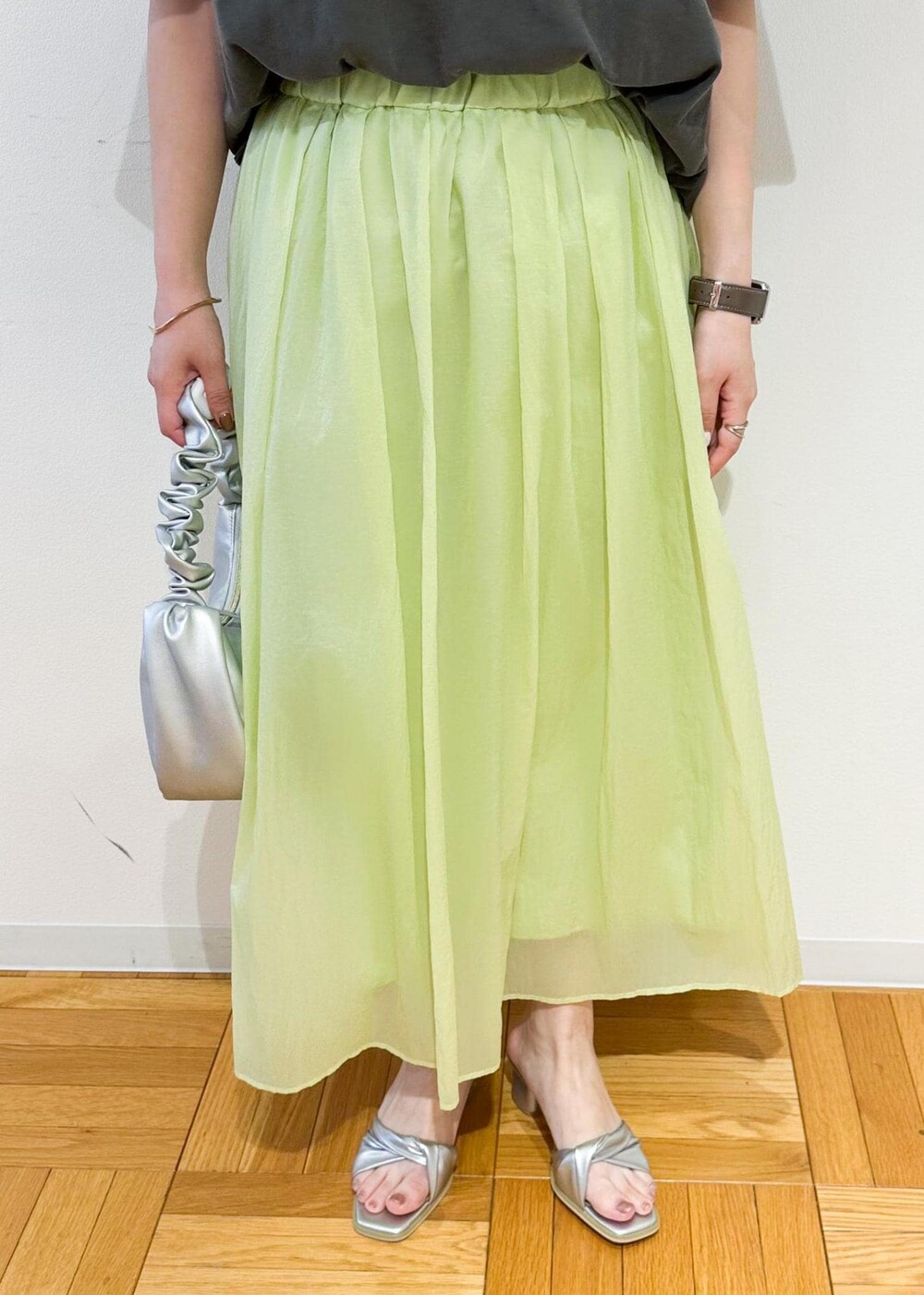 シルバー系のハンドバッグ、シルバー系のサンダル、グリーン系のスカートを着用したレディースの夏コーディネートの6枚目の写真
