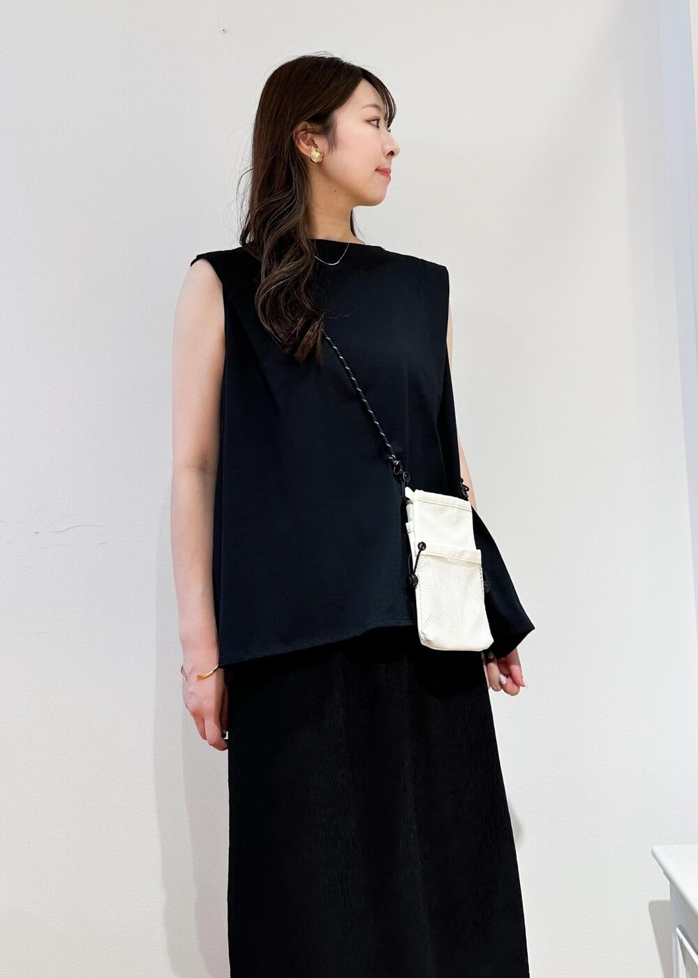 ホワイト系のショルダーバッグ、ブラック系のスカート、ホワイト系のサンダルを着用したレディースの春コーディネートの5枚目の写真