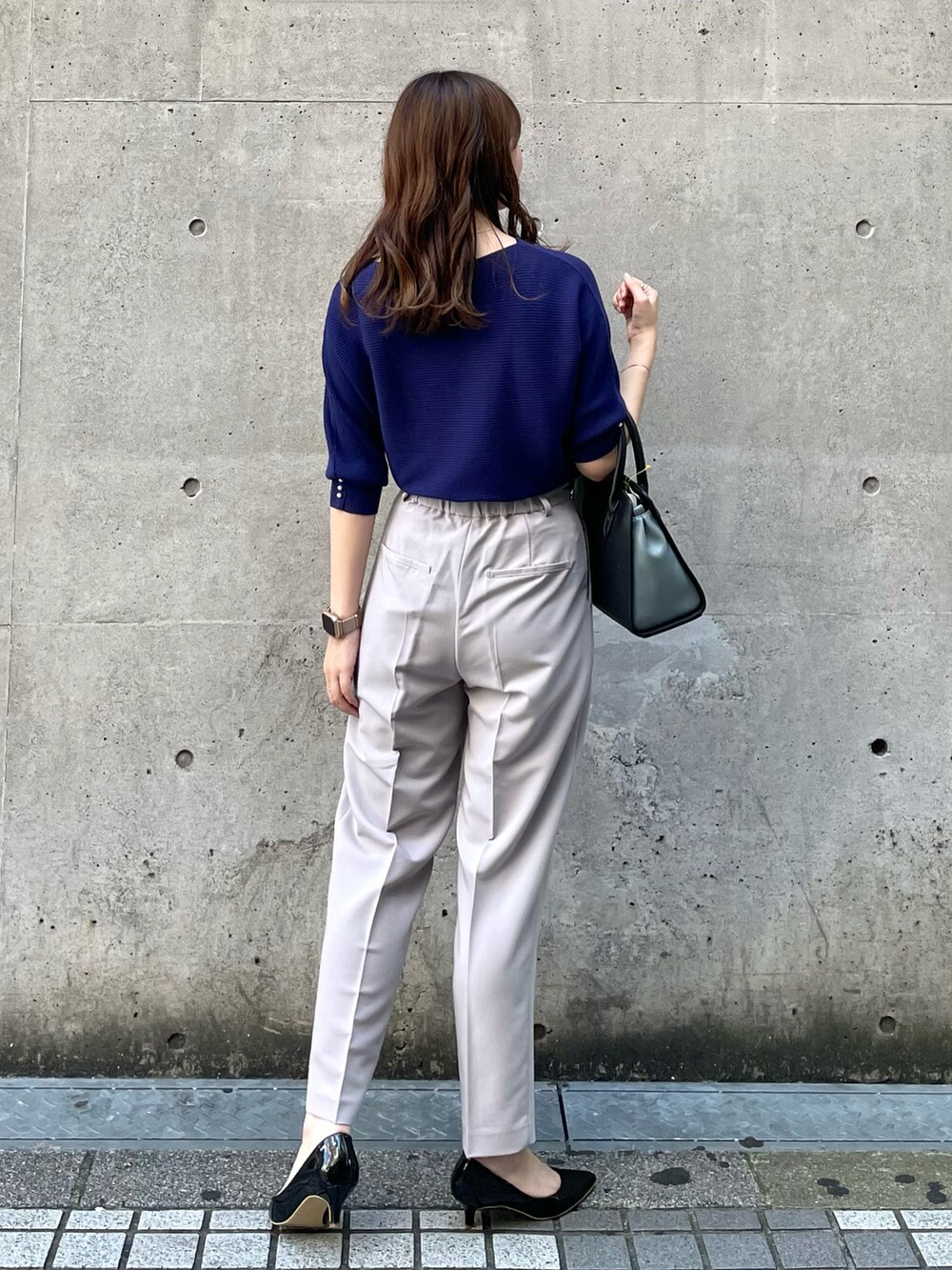 パープル系のニット/セーター、グレー系のその他パンツ、ブラック系のショルダーバッグを着用したレディースの秋コーディネートの2枚目の写真