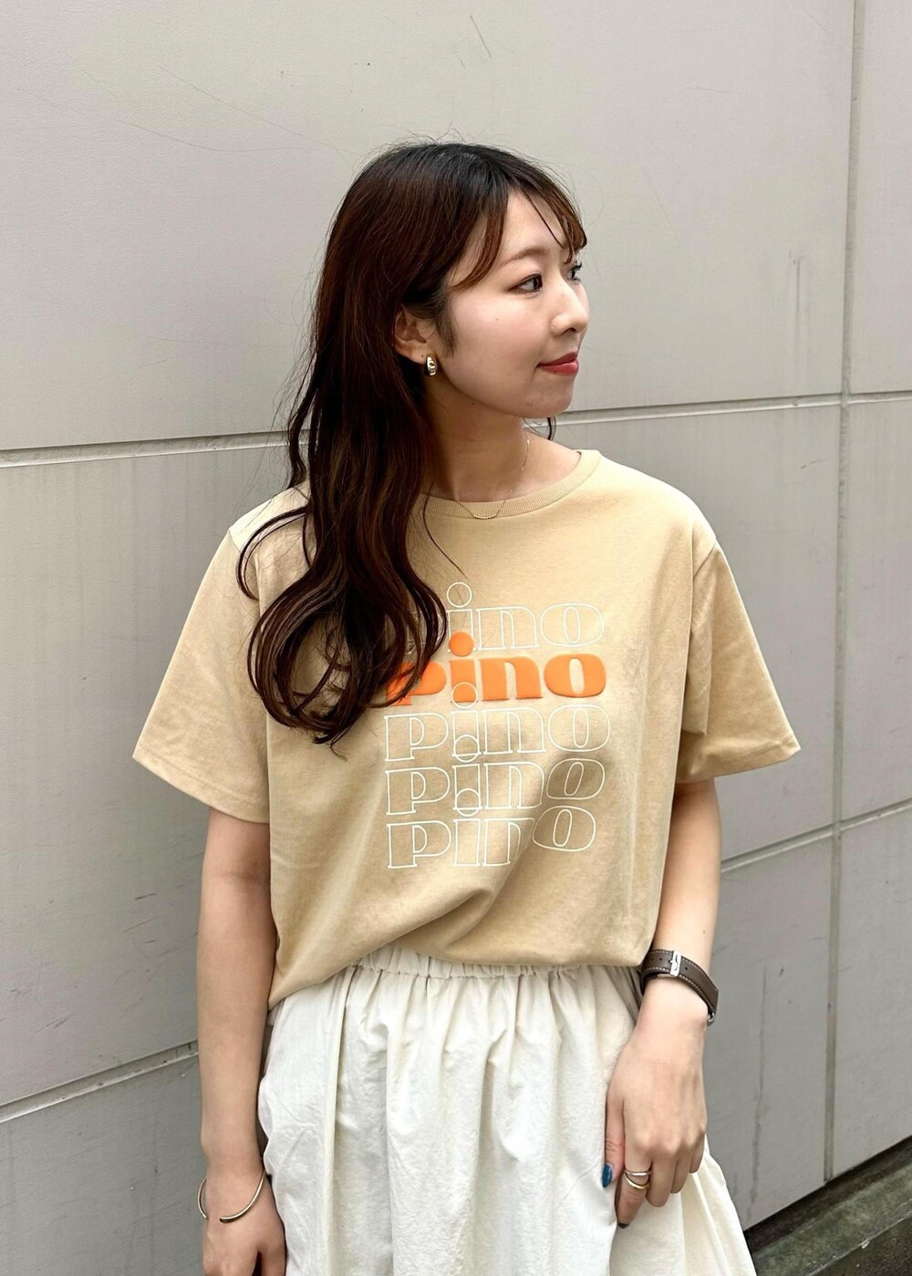 ベージュ系のTシャツ/カットソー、ホワイト系のスカート、ホワイト系のトートバッグを着用したレディースの春コーディネートの3枚目の写真