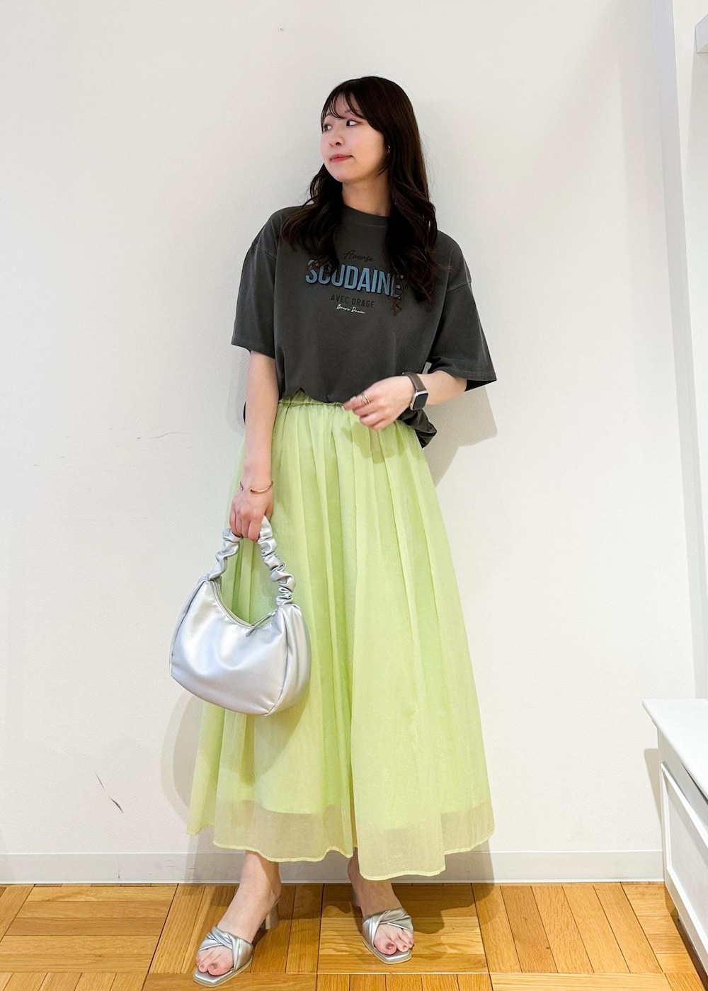 シルバー系のハンドバッグ、シルバー系のサンダル、グリーン系のスカートを着用したレディースの夏コーディネートの2枚目の写真