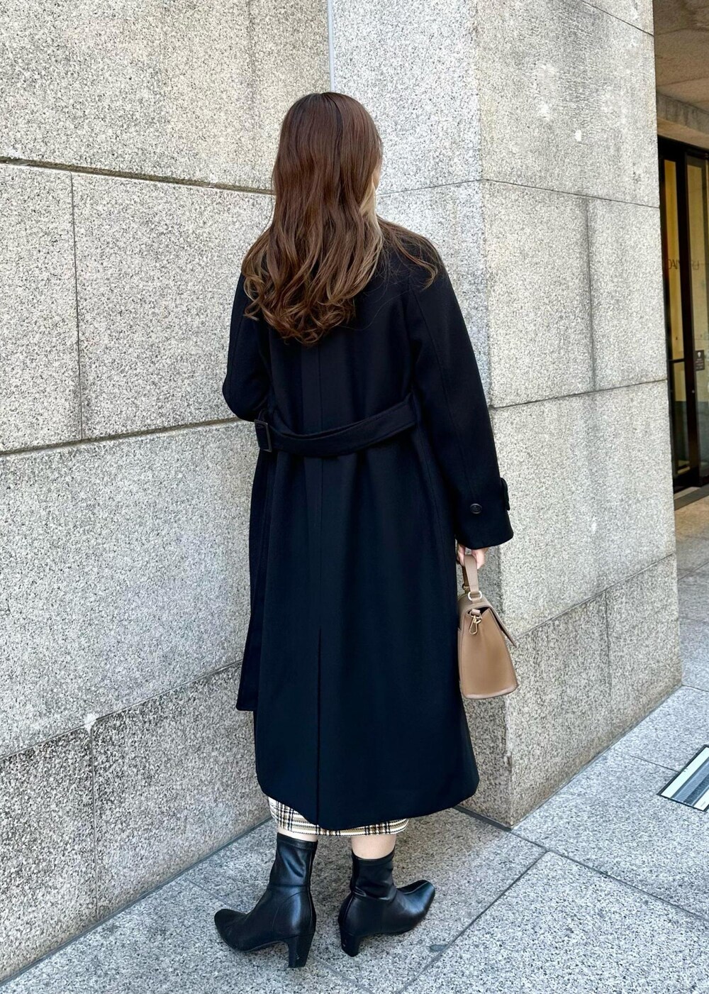 ブラウン系のショルダーバッグ、ブラック系のその他アウター、ホワイト系のスカートを着用したレディースの冬コーディネートの3枚目の写真