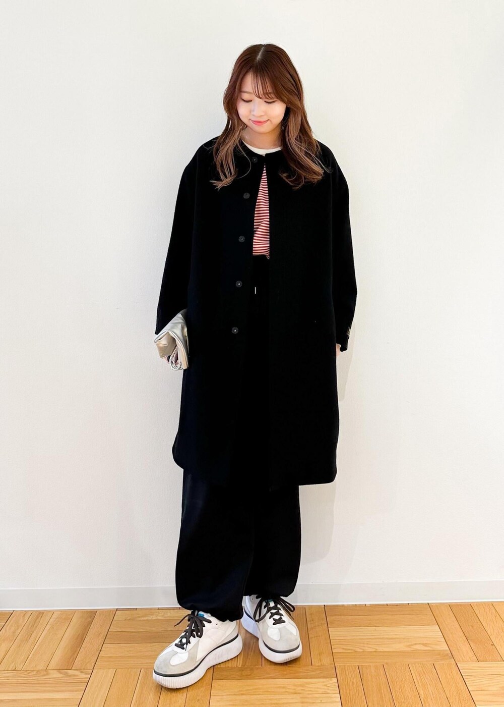レッド系のTシャツ/カットソー、ブラック系のノーカラーコート、シルバー系のトートバッグを着用したレディースの冬コーディネートの2枚目の写真