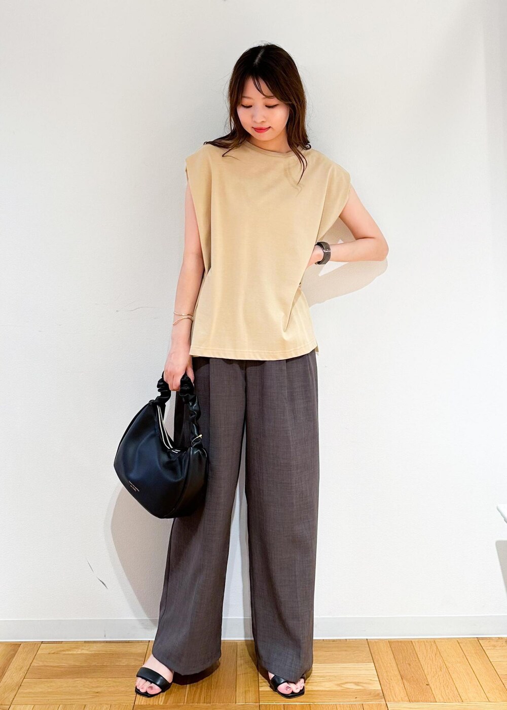 ベージュ系のTシャツ/カットソー、ブラウン系のその他パンツ、ブラック系のハンドバッグを着用したレディースの夏コーディネートの2枚目の写真