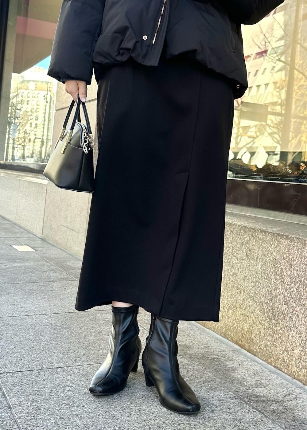 ブルー系のニット/セーター、ブラック系のダウンジャケット/コート、ブラック系のショルダーバッグを着用したレディースの冬コーディネートの6枚目の写真