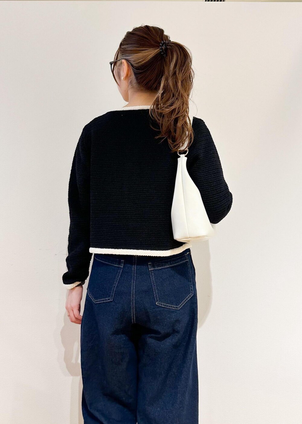 ホワイト系のショルダーバッグ、ブルー系のデニムパンツ、ブラック系のカーディガン/ボレロを着用したレディースの冬コーディネートの5枚目の写真