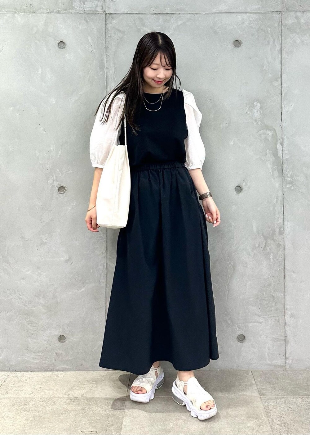 ホワイト系のトートバッグ、ブラック系のスカート、ブラック系のTシャツ/カットソーを着用したレディースの夏コーディネートの2枚目の写真