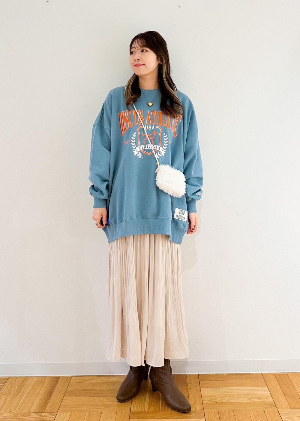 ベージュ系のスカート、ホワイト系のショルダーバッグ、グリーン系のスウェットを着用したレディースの秋コーディネートの2枚目の写真