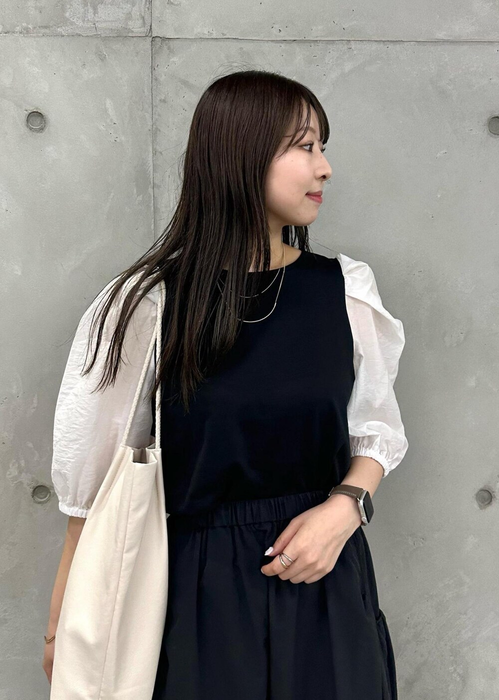 ホワイト系のトートバッグ、ブラック系のスカート、ブラック系のTシャツ/カットソーを着用したレディースの夏コーディネートの4枚目の写真