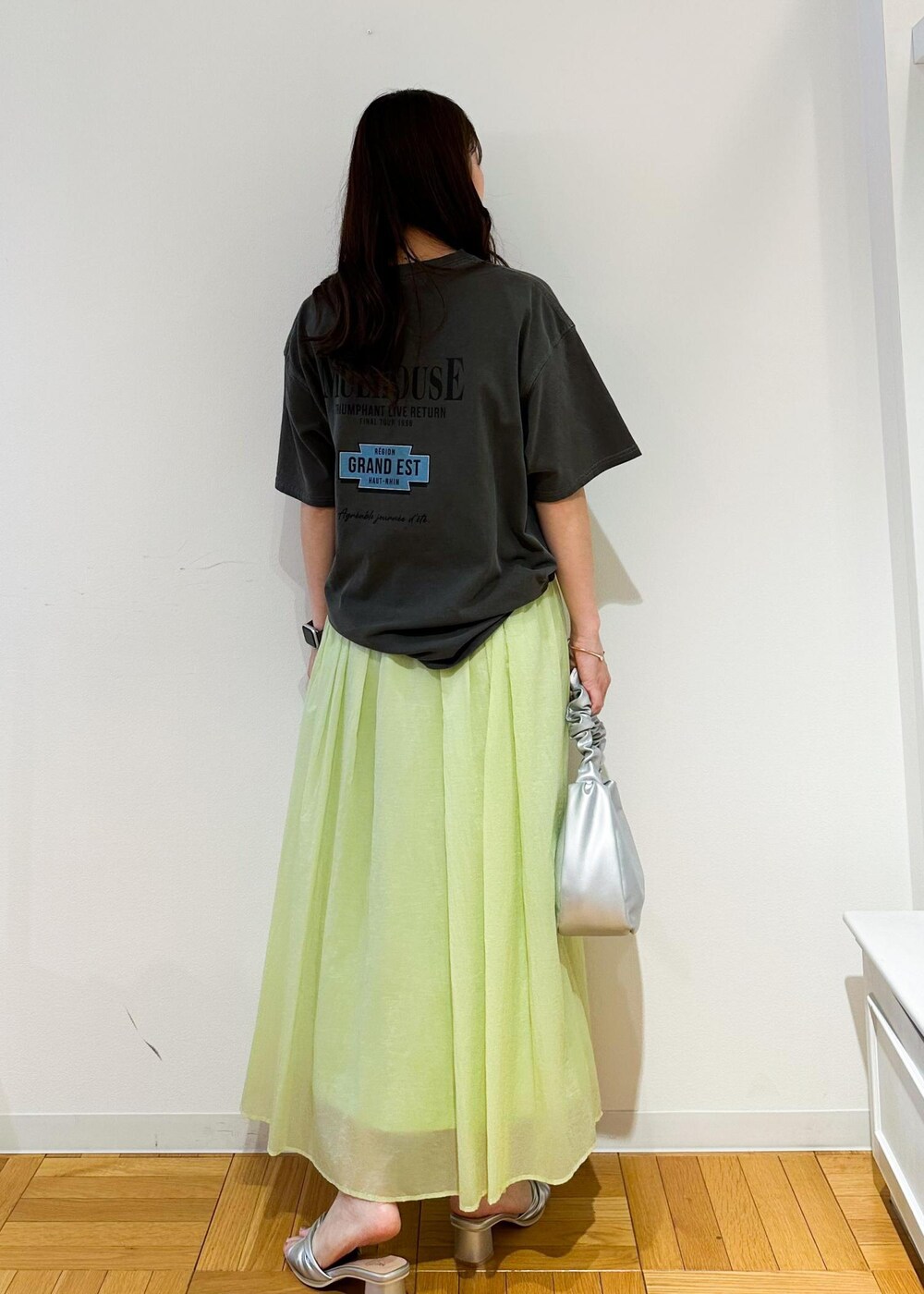 シルバー系のハンドバッグ、シルバー系のサンダル、グリーン系のスカートを着用したレディースの夏コーディネートの3枚目の写真