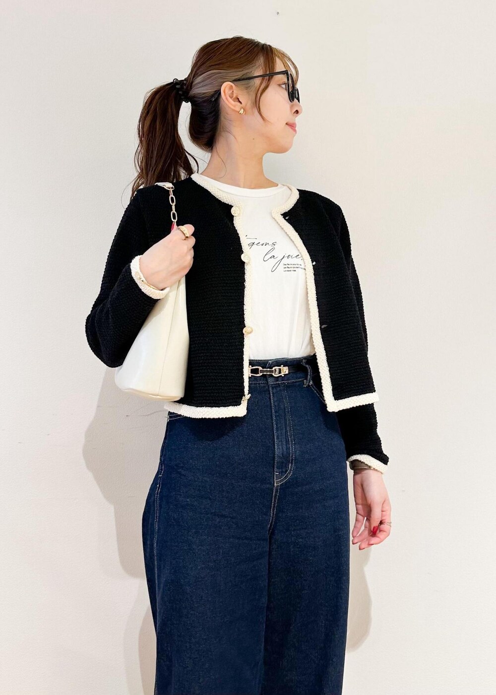 ホワイト系のショルダーバッグ、ブルー系のデニムパンツ、ブラック系のカーディガン/ボレロを着用したレディースの冬コーディネートの4枚目の写真