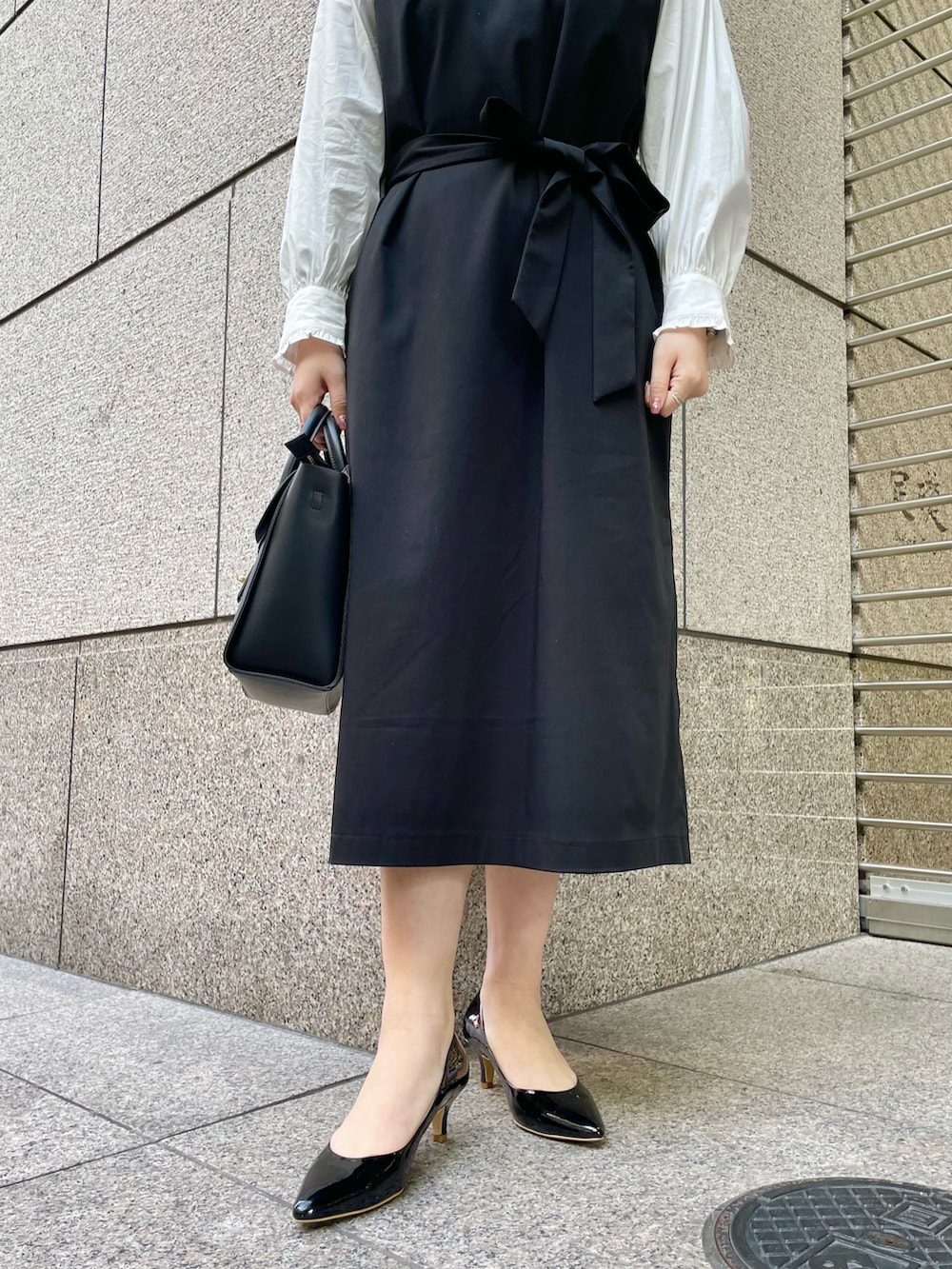 ホワイト系のシャツ/ブラウス、ブラック系のジャンパースカート、ブラック系のパンプスを着用したレディースの冬コーディネートの5枚目の写真