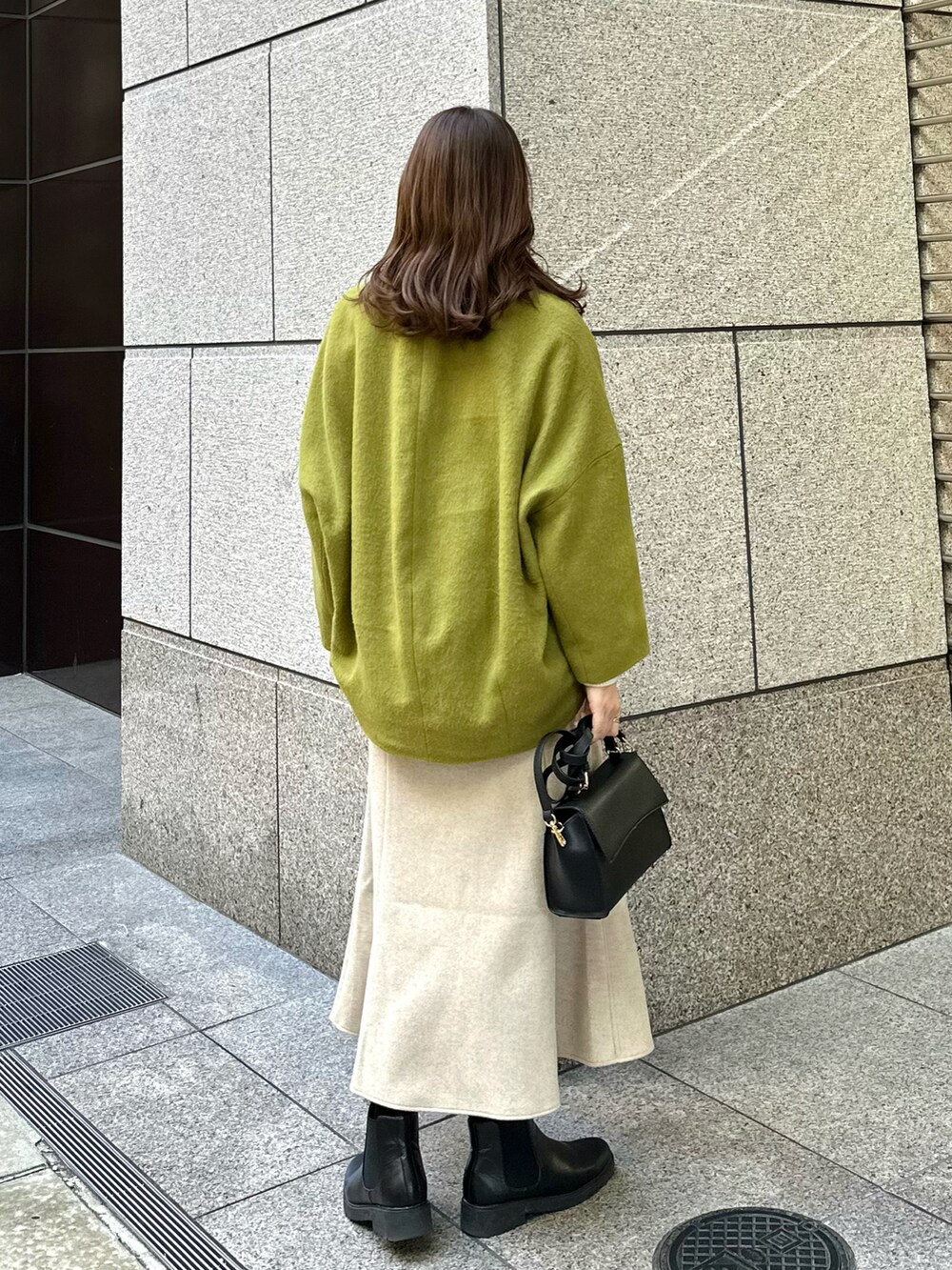 イエロー系のその他アウター、ベージュ系のスカート、ホワイト系のニット/セーターを着用したレディースの冬コーディネートの2枚目の写真