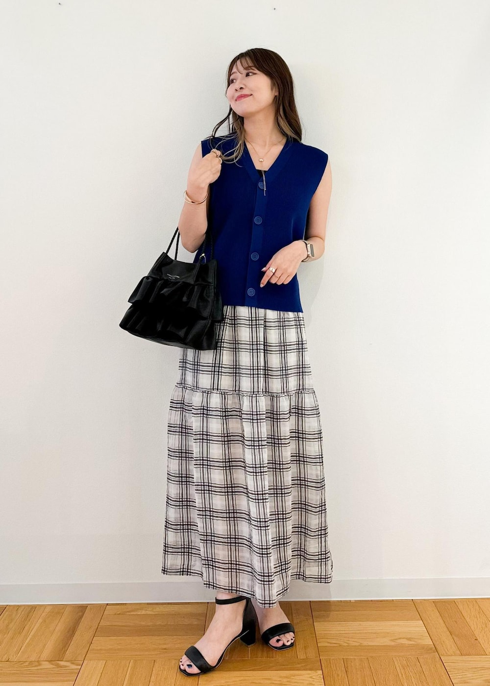 ブラック系のトートバッグ、ブルー系のベスト、ブラック系のスカートを着用したレディースの夏コーディネートの2枚目の写真